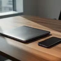 Ein geschlossener Laptop und ein Smartphone auf einem minimalistischen Bürotisch in einer ruhigen Arbeitsumgebung. - Foto: über boerse-global.de