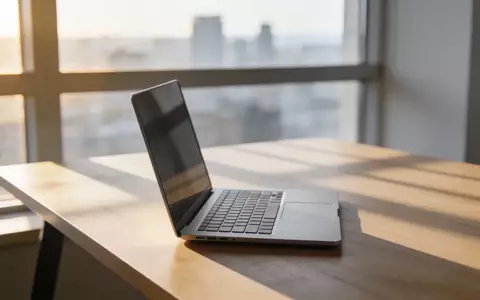 Minimalistischer Arbeitsplatz mit Laptop vor einem unscharfen Stadtpanorama bei natürlichem Tageslicht. - Foto: über boerse-global.de