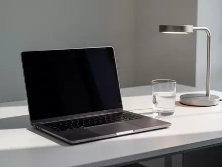 Ein moderner, aufgeräumter Schreibtisch mit einem zugeklappten Laptop und einer Schreibtischlampe in einer Büroumgebung. - Foto: über boerse-global.de