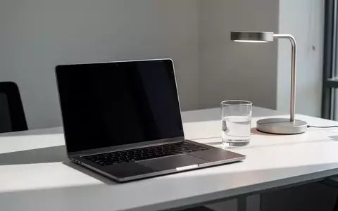 Ein moderner, aufgeräumter Schreibtisch mit einem zugeklappten Laptop und einer Schreibtischlampe in einer Büroumgebung. - Foto: über boerse-global.de