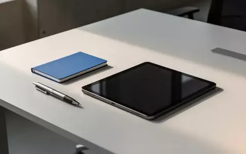 Ein minimalistischer Büroarbeitsplatz mit einem blauen Notizbuch und einem Tablet auf einem Schreibtisch bei natürlichem Licht. - Foto: über boerse-global.de
