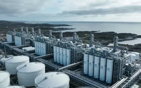 Moderne Wasserstoff-Produktionsanlage in einer weitläufigen Küstenlandschaft bei bewölktem Himmel. - Foto: über boerse-global.de