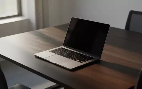 Ein moderner, minimalistischer Arbeitsplatz mit einem Laptop auf einem dunklen Holztisch bei natürlichem Tageslicht. - Foto: über boerse-global.de