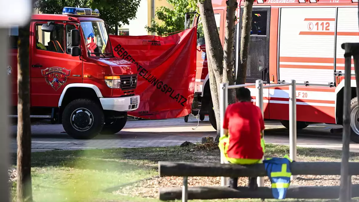 Ein Feuerwehrmann sitzt in der Nähe des Tatorts.  - Bild: Britta Pedersen/dpa