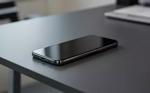Ein modernes Smartphone liegt auf einem dunklen Schreibtisch, der Bildschirm ist dunkel und reflektiert das Umgebungslicht. - Foto: über boerse-global.de