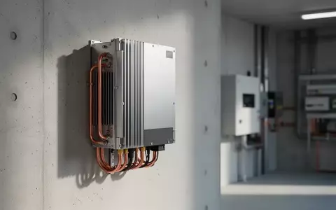 Ein moderner Hybrid-Wechselrichter montiert an einer hellen Betonwand in einem technischen Versorgungsraum. - Foto: über boerse-global.de