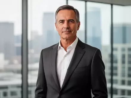 Ein professionell gekleideter Geschäftsmann in einem modernen Bürogebäude mit Blick auf eine Skyline. - Foto: über boerse-global.de