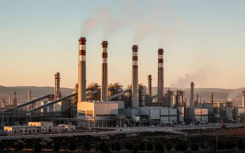 Moderne Industrieanlage mit hohen Schornsteinen vor einem klaren Himmel als Symbol für die neue Emissionshandelsverordnung. - Foto: über boerse-global.de