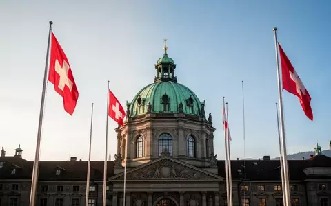 Das Bundeshaus in Bern bei Tageslicht mit Blick auf die Kuppel und die Schweizer Flaggen. - Foto: über boerse-global.de