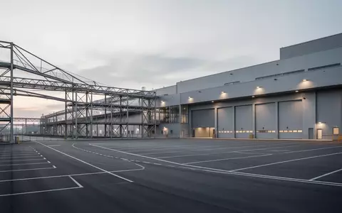 Weitläufiges Industriegelände mit modernen Produktionshallen und logistischer Infrastruktur bei Dämmerung. - Foto: über boerse-global.de
