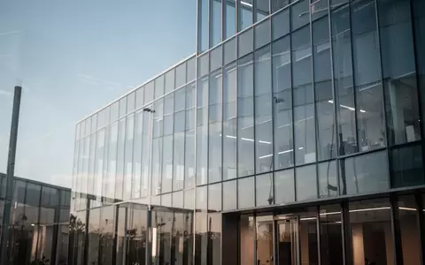 Modernes Glasgebäude bei Tageslicht, das die fortschreitende Digitalisierung im Finanzsektor symbolisiert. - Foto: über boerse-global.de