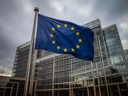Die Flagge der Europäischen Union weht vor einem modernen Bürogebäude in Brüssel bei bewölktem Himmel. - Foto: über boerse-global.de