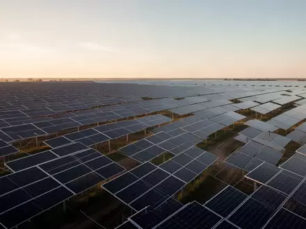 Reihen von Photovoltaik-Paneelen in einem Solarpark bei goldenem Sonnenlicht. - Foto: über boerse-global.de