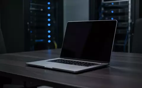 Ein minimalistischer Arbeitsplatz mit einem Laptop auf einem dunklen Holztisch in einem schwach beleuchteten Büro. - Foto: über boerse-global.de