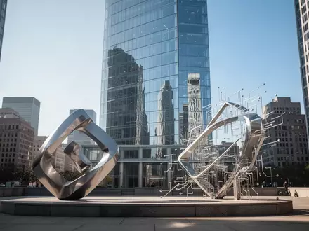 Ein modernes Hochhaus in einem Finanzviertel mit einer abstrakten Metallskulptur im Vordergrund bei Tageslicht. - Foto: über boerse-global.de