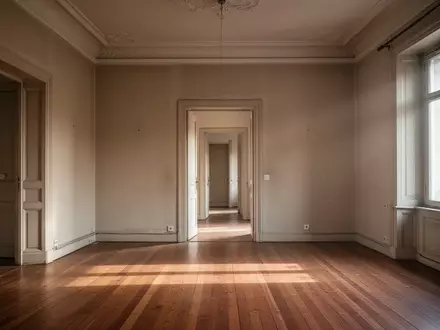 Ein leeres, lichtdurchflutetes Wohnzimmer in einer Altbauwohnung mit Parkettboden und Blick in einen Flur. - Foto: über boerse-global.de