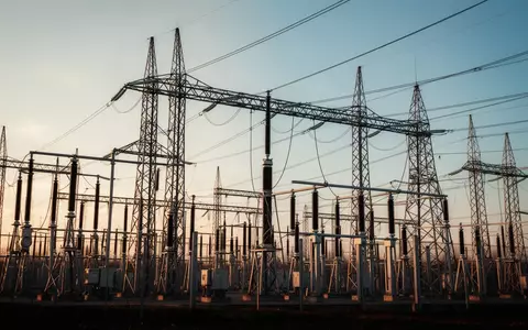 Moderne Hochspannungsanlage mit Strommasten und Leitungen vor einem klaren Himmel. - Foto: über boerse-global.de