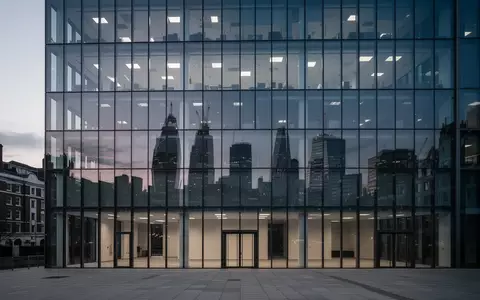 Moderne Glasfassade eines Bürogebäudes in London bei Dämmerung, das die Skyline reflektiert. - Foto: über boerse-global.de