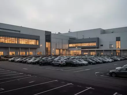 Außenansicht eines modernen Volkswagen-Automobilwerks bei Dämmerung mit Fabrikhallen und leeren Parkplätzen. - Foto: über boerse-global.de