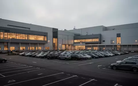 Außenansicht eines modernen Volkswagen-Automobilwerks bei Dämmerung mit Fabrikhallen und leeren Parkplätzen. - Foto: über boerse-global.de