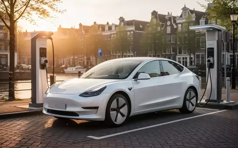 Ein weißes Elektroauto steht an einer modernen Ladestation in einer niederländischen Stadt bei Sonnenuntergang. - Foto: über boerse-global.de