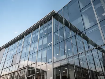 Ein modernes Bürogebäude mit Glasfassade vor einem klaren blauen Himmel. - Foto: über boerse-global.de