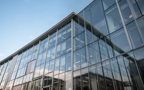 Ein modernes Bürogebäude mit Glasfassade vor einem klaren blauen Himmel. - Foto: über boerse-global.de