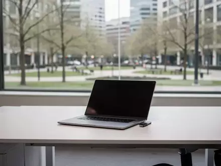 Ein minimalistischer, leerer Schreibtisch mit einem geschlossenen Laptop vor einem hellen Fenster mit Blick ins Grüne. - Foto: über boerse-global.de
