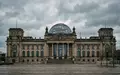 Die gläserne Kuppel des Reichstagsgebäudes in Berlin bei bewölktem Himmel. - Foto: über boerse-global.de