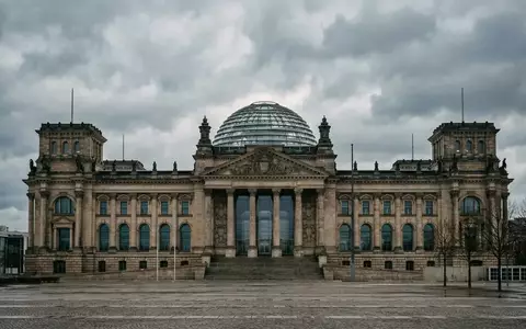 Die gläserne Kuppel des Reichstagsgebäudes in Berlin bei bewölktem Himmel. - Foto: über boerse-global.de