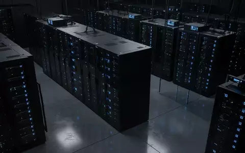 Dunkler Serverraum mit schwarzen Server-Racks und dezenten blauen Status-LEDs in einer modernen Industrieumgebung. - Foto: über boerse-global.de