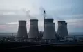 Ein großes Kohlekraftwerk mit Kühltürmen in einer weitläufigen Industrielandschaft bei Tagesanbruch. - Foto: über boerse-global.de