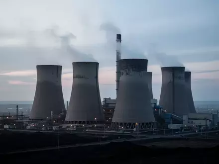 Ein großes Kohlekraftwerk mit Kühltürmen in einer weitläufigen Industrielandschaft bei Tagesanbruch. - Foto: über boerse-global.de