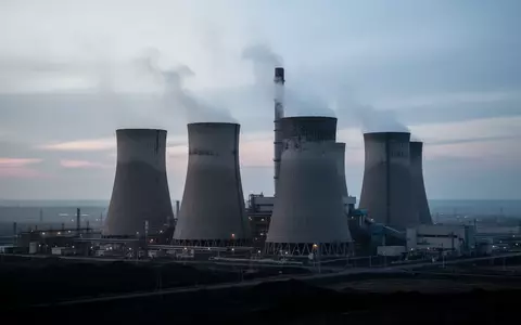 Ein großes Kohlekraftwerk mit Kühltürmen in einer weitläufigen Industrielandschaft bei Tagesanbruch. - Foto: über boerse-global.de