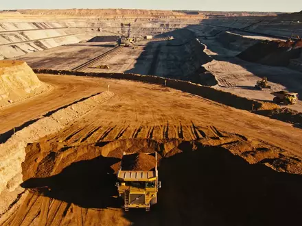 Ein weitlĂ€ufiges Lithium-Bergwerk in der Abendsonne mit Baumaschinen vor einer bergigen Landschaft. - Foto: ĂŒber boerse-global.de