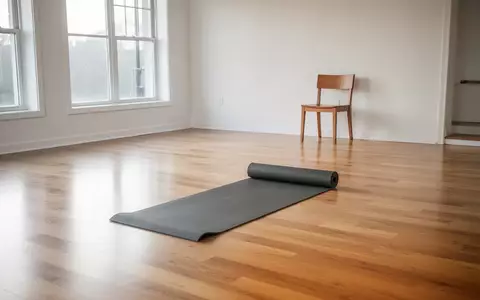 Ein heller, minimalistischer Fitnessraum mit einer ausgerollten Yogamatte und einem leeren Stuhl im Hintergrund. - Foto: über boerse-global.de