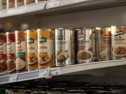 Mehrere Metallkonservendosen in einem Supermarktregal bei natürlichem Licht. - Foto: über boerse-global.de