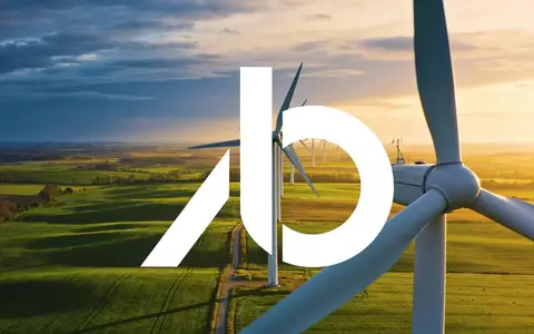 Moderne Windkraftanlagen in einer weitläufigen grünen Landschaft bei Sonnenuntergang als Symbol für erneuerbare Energien. - Foto: über boerse-global.de