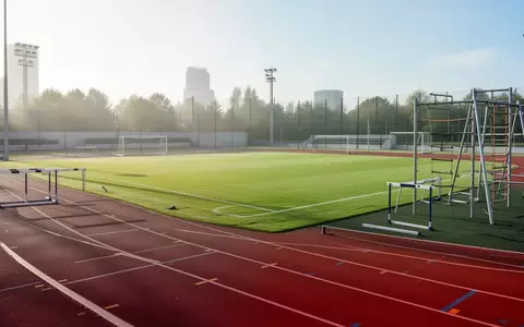 Leere Sportanlage mit Laufbahn und Rasenplatz bei hellem Tageslicht für Breitensportangebote. - Foto: über boerse-global.de