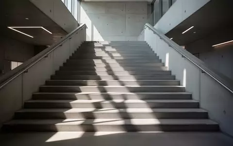 Ein leeres, modern gestaltetes Treppenhaus mit natürlichem Lichteinfall und geometrischen Schatten auf den Stufen. - Foto: über boerse-global.de