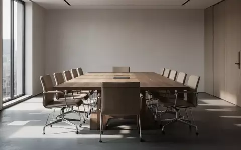 Ein minimalistisch gestalteter Konferenzraum mit leerem Holztisch und einfallendem Tageslicht, das geometrische Schatten wirft. - Foto: über boerse-global.de