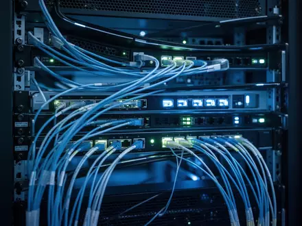 Moderne Serverinfrastruktur mit blau beleuchteten Glasfaserkabeln und technischer Hardware in einem Rechenzentrum. - Foto: über boerse-global.de