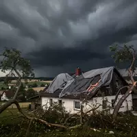 Ein durch ein schweres Unwetter beschädigtes Wohnhaus mit abgedecktem Dach vor einem dunklen, gewittrigen Himmel. - Foto: über boerse-global.de