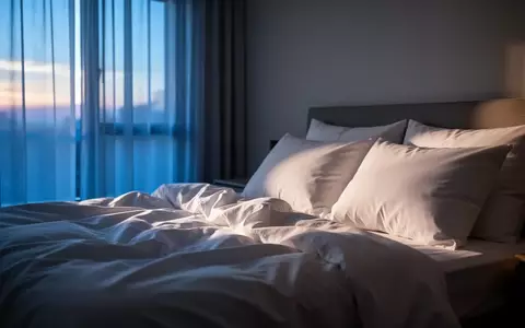 Ein ungemachtes Bett in einem ruhig beleuchteten Schlafzimmer bei Morgendämmerung, das eine Atmosphäre der Erholung vermittelt. - Foto: über boerse-global.de