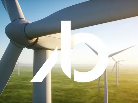 Moderne Windkraftanlagen in einer weitläufigen, grünen Landschaft bei klarem Himmel. - Foto: über boerse-global.de
