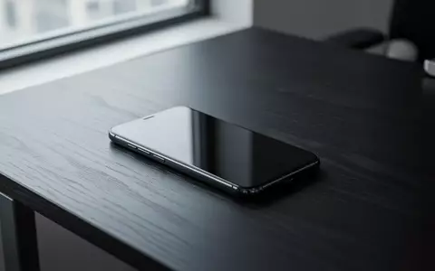 Ein modernes Smartphone liegt auf einem dunklen Holztisch in einem minimalistisch eingerichteten Büro. - Foto: über boerse-global.de