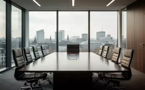 Moderner, leerer Konferenzraum in einem Bürogebäude mit einem großen Holztisch und Blick auf eine Stadtkulisse. - Foto: über boerse-global.de