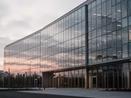 Ein minimalistisches Glas- und Stahlgebäude bei Dämmerung, das eine ruhige, professionelle Unternehmensatmosphäre ausstrahlt. - Foto: über boerse-global.de