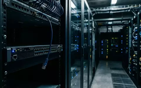 Ein Serverraum mit blinkenden Lichtern an Netzwerkschränken, wobei ein Ethernet-Kabel lose aus einem Switch hängt. - Foto: über boerse-global.de