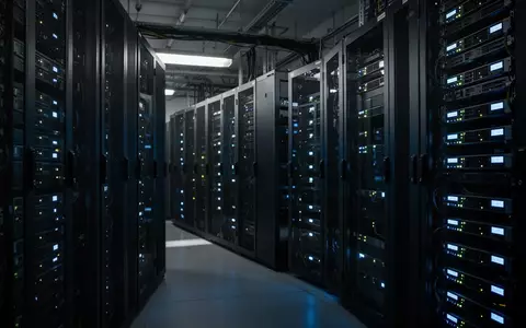 Server-Racks in einem Berliner Rechenzentrum mit blinkenden Statusleuchten in einer dunklen, industriellen Umgebung. - Foto: über boerse-global.de
